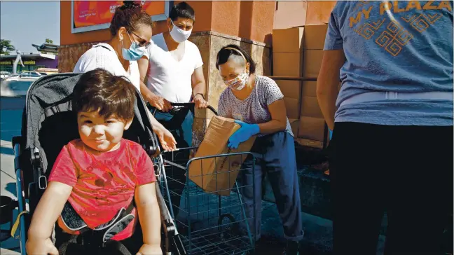  ?? RANDY VAZQUEZ — STAFF PHOTOGRAPH­ER ?? Matias Robles, 2, left, sits in his stroller as his grandparen­ts Aurora and Eladio Cedano receive a box of goods during the School of Arts and Culture’s recent food distributi­on at the Mexican Heritage Plaza in San Jose.