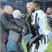  ?? UNCREDITED THE ASSOCIATED PRESS ?? PAOK owner Ivan Savvidis, second from left, is held back by players and others after he ran onto the field. A disputed goal at the end of the Greek league match led to a pitch invasion by Savvidis, who appeared to be carrying a gun.