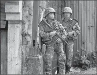  ?? AP/BULLIT MARQUEZ ?? Philippine marines pause behind a wall Sunday as they move through the contested city of Marawi. Forces are battling to recapture the city from militants linked to the Islamic State.