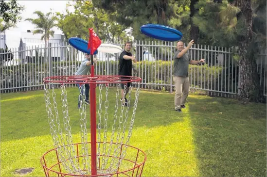  ?? Gina Ferazzi Los Angeles Times ?? IN A NOD to the digital age, Wham-O is developing a Frisbee app. Above, employees play with new Frisbees this month at the company’s headquarte­rs in Carson.