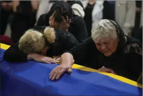  ?? AP PHOTOS ?? The mother, right, and sister of Army Col. Oleksander Makhachek mourn over the coffin with his remains during a funeral service in Zhytomyr, Ukraine, Friday. According to combat comrades Makhachek was killed fighting Russian forces when a shell landed in his position on Monday.