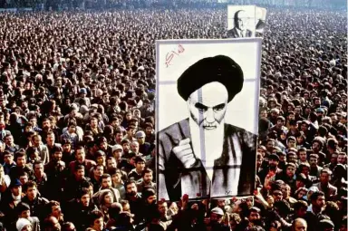  ?? 1º.jan.79/AFP ?? Iranianos protestam em Teerã contra o xá Reza Pahlevi e seguram imagem do aiatolá Khomeini, que vivia no exílio
