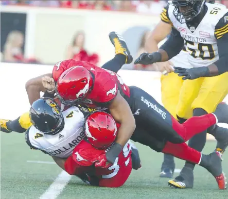  ?? JIM WELLS ?? Tiger-Cats quarterbac­k Zach Collaros is sacked by the Stampeders’ Charleston Hughes and James Vaughters Saturday in Calgary.