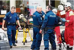  ?? —AFP ?? Under control: Police officers standing guard as rescue personnel tend to a stabbing victim in Turku.