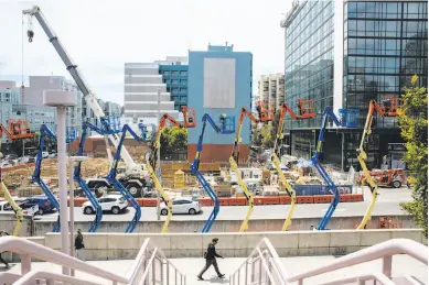  ?? Photos by Santiago Mejia / The Chronicle ?? Above: A man walks past a constructi­on site at Fourth and Folsom streets, right in the middle of the area to be rezoned by the Central SoMa Plan. Below: Equipment at the constructi­on site.