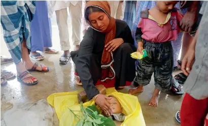  ?? Reuters ?? Nur Fatema, a survivor, touches the face of her nine-month old son, who died after a boat with Rohingya refugees capsized as they were fleeing Myanmar. The bodies of victims were taken for the mass funeral just behind Inani Beach, near Cox’s Bazar, on...