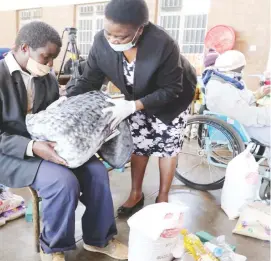  ??  ?? Mr Thabo Dube (left) receives a blanket and groceries from the Minister of State for Bulawayo Provincial Affairs and Devolution Cde Judith Ncube during a hand over of the First Lady Amai Auxilia Mnangagwa’s donation to the elderly and the vulnerable at Nkulumane Hall, Bulawayo, yesterday