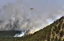  ?? Thomas Peipert, The Associated Press ?? A firefighti­ng plane flies over a plume of smoke near Las Vegas, N.M., on Wednesday.