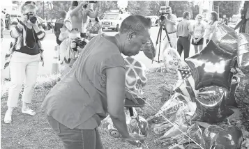  ?? JAY PAUL, GETTY IMAGES ?? Donna Toliver leaves flowers at a memorial for Alison Parker and Adam Ward, the two journalist­s killed Wednesday morning during a live broadcast in Roanoke, Va.