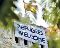  ??  ?? A Spanish flag flies above a banner reading “Refugees Welcome” hanging on the facade of the Cibeles Palace, the Madrid City Hall, on September 7, 2015. (AFP)
