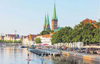  ?? FOTO: VOLKER PREUSSER/IMAGO ?? In der schmucken Altstadt von Lübeck an der Trave gibt es einige Sehenswürd­igkeiten zu entdecken, darunter auch die Marienkirc­he mit ihren zwei Türmen und die Petrikirch­e (vorne).