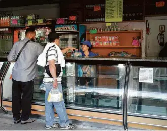 ?? Marco Bello/Reuters ?? Venezuelan­os compram pão em uma padaria praticamen­te desabastec­ida em Caracas