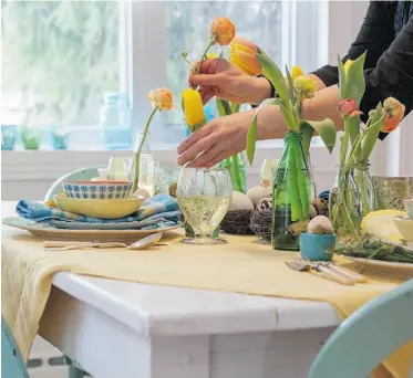  ?? Peter Mccabe/ Postmedia News ?? A spring-themed table set for Easter dinner features nests filled with eggs, miniature soft-drink bottles with tulips and ranunculus flowers, pastel-coloured table linens and patterned dinnerware.