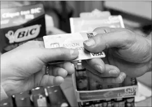  ?? — Photo by The Canadian Press ?? A consumer pays with a credit card at a store in Montreal.