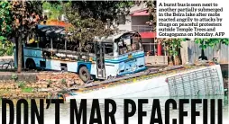 ?? ?? A burnt bus is seen next to another partially submerged in the Beira lake after mobs reacted angrily to attacks by thugs on peaceful protesters outside Temple Trees and Gotagogama on Monday. AFP