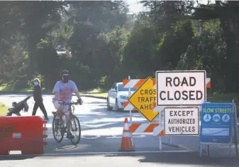  ?? Lea Suzuki / The Chronicle ?? A bicyclist rides past signs at the intersecti­on of MLK Drive and 41st Avenue.