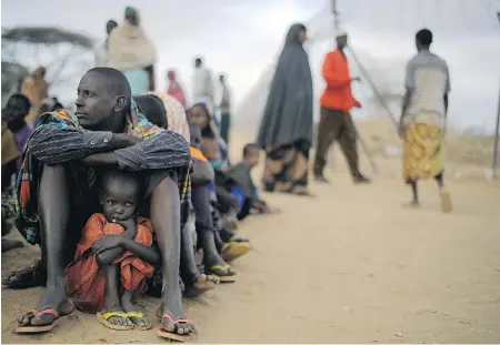  ?? TONY KARUMBA / AFP / GETTY IMAGES FILES ?? A Somali father and daughter wait for help, displaced from their home by famine. Aid agencies in Somalia are warning that hundreds of thousands of people face potential starvation, yet thousands are making precarious sea crossings from Yemen to seek...