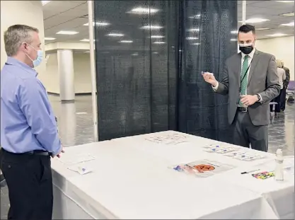  ?? Photos by Lori Van Buren / Times Union ?? Albany Internatio­nal Airport manager Fred Acunto, left, assists Matt Cannon, director of government and developmen­tal affairs for the Airport Authority, as Cannon takes a COVID-19 saliva test.