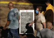  ?? ERIC GAY — THE ASSOCIATED PRESS FILE ?? On March 3, visitors wearing face masks walk past a sign requiring masks at a restaurant along the River Walk in San Antonio.