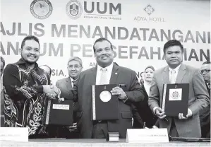  ??  ?? AHMAD Bashah menyaksika­n pertukaran dokumen perjanjian Memerandum Persefaham­an (MoU) antara Mohamed Mustafa (tengah) bersama Faiz (kiri) dan Nor Saidi di Langkawi. — Gambar Bernama