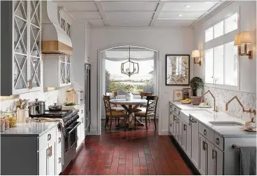  ?? Creators Syndicate photo ?? You can begin the design of such a kitchen space by keeping the color scheme very light and neutral. This example has features and walls in soft whites and is anchored by a rich brown tile floor.