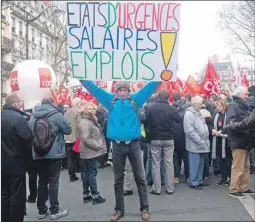  ?? AP PHOTO ?? A protester holds a banner reading “State of emergency Salaries, Jobs” as he takes part in a demonstrat­ion in Paris on Tuesday.