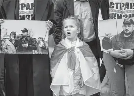  ?? Mindaugas Kulbis / Associated Press ?? A girl wearing an Old Belarusian flag and other Belarusian expats attend a protest in Lithuania demanding freedom for political prisoners in Belarus.