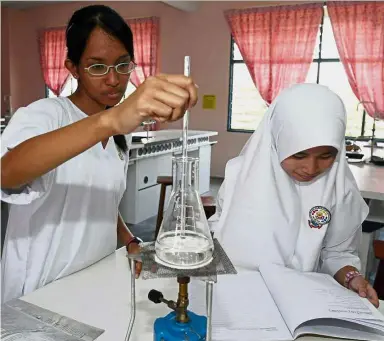  ??  ?? Students in the midst of a chemistry experiment in the school laboratory. — File photo