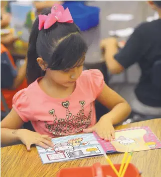  ?? ADOLPHE PIERRE-LOUIS/JOURNAL ?? Barcelona Elementary first-grade student Ailin Frayre, 5, reads during the summer program at the South Valley school. APS was hit hard by reductions in state funding for the “K-3 Plus” program.