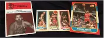  ?? THE NEWS-HERALD ?? Reprints of 1961 Fleer Wilt Chamberlai­n and 1986-87 Fleer Michael Jordan flank an original 1980-81Topps Larry Bird-Magic Johnson rookie card.