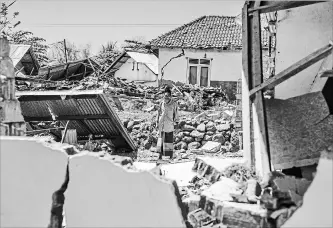  ?? FAUZY CHANIAGO
THE ASSOCIATED PRESS ?? A man inspects a village destroyed by the deadly earthquake in Kayangan, Lombok Island, Indonesia, Monday.