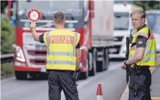  ?? FOTO: DPA ?? Polizisten kontrollie­ren Fahrzeuge, die aus Österreich nach Deutschlan­d kommen. Transportu­nternehmen befürchten massive Einbußen durch strengere Grenzkontr­ollen und lange Staus.