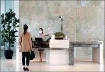  ??  ?? A front desk clerk asks a guest to face a temperatur­e scanner at Kerry Hotel, Hong Kong.