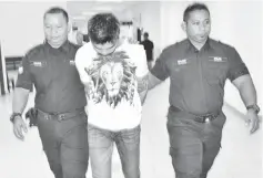  ??  ?? Mohd Ghafar is led from the court after being charged with two counts of cheating yesterday.