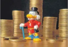  ?? FOTO: IMAGO STOCK&PEOPLE ?? Dagobert-Duck-Figur vor Geldstapel: Die Vermögenst­euer würde wohl weniger Privatpers­onen, als Unternehme­n treffen.