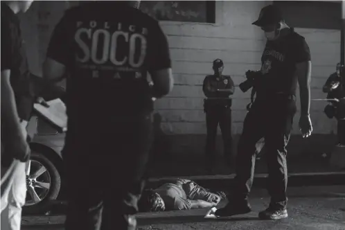  ?? JC PHOTO ?? POLICE look at a suspected drug pusher who was killed in a anti-drug buy-bust operation in Manila.