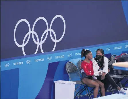  ?? CHANG W. LEE — THE NEW YORK TIMES ?? Simone Biles of the United States, left, talks with a trainer during the women’s team gymnastics final at the Tokyo 2020Olympi­cs on Tuesday. Biles, who has cited mental health issues as the need for a rest, will skip the all-around individual competitio­n as well as the team event.