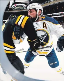  ?? MADDIE MEYER GETTY IMAGES ?? Zach Bogosian, right, of the Buffalo Sabres checks Danton Heinen of the Bruins into the boards at TD Garden in Boston Sunday.Jack Eichel and Jeff Skinner extended their points streaks to six games.