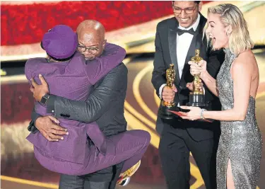  ?? CHRIS PIZZELLO CHRIS PIZZELLO/INVISION/AP ?? Spike Lee, co-winner of Best Adapted Screenplay for BlacKkKlan­sman, jumps into the arms Samuel L. Jackson as presenter Brie Larson looks on during Sunday night’s ceremony in Los Angeles. It was the first Academy Award for Lee.