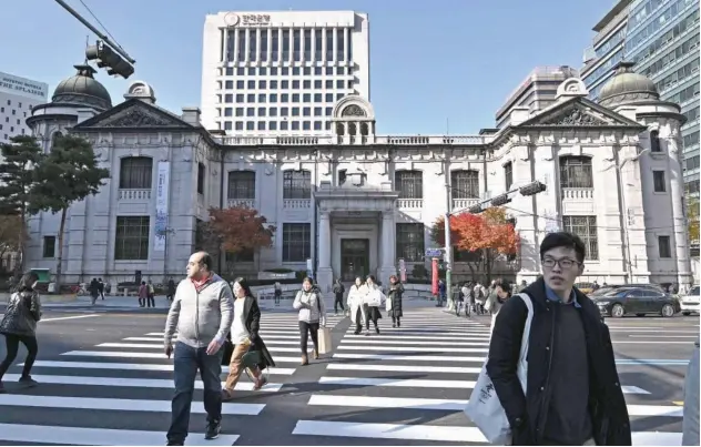  ?? File/agence France-presse ?? ↑
Pedestrian­s cross a road in front of the Bank of Korea building in Seoul.