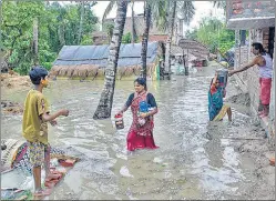  ?? AFP/PTI ?? (Top) Residents shift makeshift stalls as water reaches the road at a beachfront area while strong winds batter Balasore district in Odisha on Wednesday. (Below) Villagers wade through a waterlogge­d and muddy street at a village after the landfall of Cyclone Yaas in West Bengal’s South 24 Paragnas.