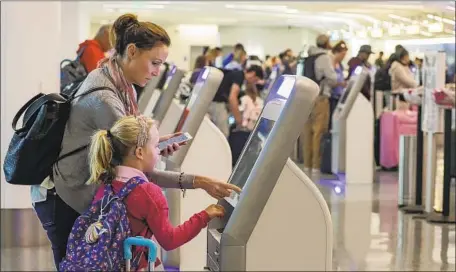  ?? Irfan Khan Los Angeles Times ?? PASSENGERS may be expected to do more self-checking. Above, Katy Von Treskow and daughter Madeline use a kiosk at LAX last year.