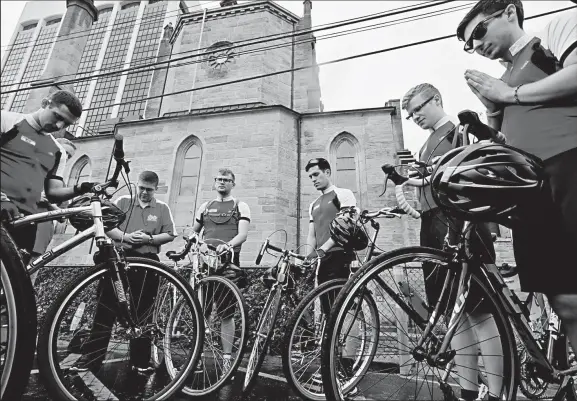  ?? DISPATCH PHOTOS ?? ERIC ALBRECHT Seminarian­s from Pontifical College Josephinum on the Far North Side pray together Downtown behind St. Joseph Cathedral before continuing their “Seek Holiness” bike tour. They were headed to St. Mary School in German Village on Wednesday.
