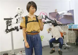  ?? — Reuters ?? Keio University student Uina Otake reacts as she tries out a remotely operated wearable system of the ‘FUSION’ project, Full Body Surrogacy for Collaborat­ive Communicat­ion, during its demonstrat­ion at the Keio University Graduate School of Media Design in Yokohama, near Tokyo, Japan.
