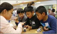  ??  ?? Sunday Friends volunteer Rin Ha, left, tutors Tyler Truong, 7, left, Ulices Lopez, 7, and Jose Damian Lopez, 5, at the computer table at Meadows Elementary School in San Jose.