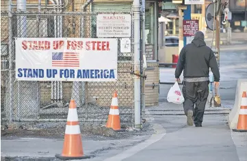  ??  ?? A man walks past a “Stand Up For Steel, Stand Up For America” sign while arriving at the United States Steel Corp. Clairton Plant coke manufactur­ing facility as emissions rise in Clairton, Pennsylvan­ia on Sunday. — WP-Bloomberg photo