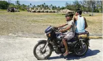  ?? AARON FAVILA / AP ?? Filipinos drive a tricycle past U.S. military vehicles at the Naval Base Camilo Osias in Santa Ana, Cagayan province, Philippine­s on May 6. Santa Ana is one of nine areas where American forces could encamp indefinite­ly and store their weapons and equipment.