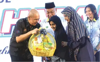  ?? — Bernama photo ?? Minister of Domestic Trade and Cost of Living Datuk Armizan Mohd Ali handing out Rahmah basket to a recipient at the KPDN Carnival Tour in Perlis on Saturday night.