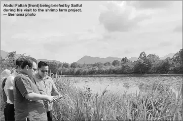  ??  ?? Abdul Fattah (front) being briefed by Saiful during his visit to the shrimp farm project. — Bernama photo