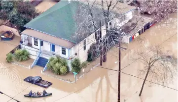  ?? — AFP photo ?? People paddle a boat through a flooded neighbourh­ood in Guernevill­e, California.